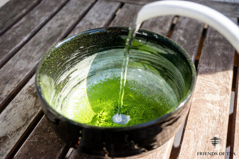 Matcha Pulver wird in einer Schüssel mit heißem Wasser aufgegossen