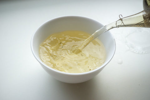 Tee wird in eine Porzellanschale gegossen